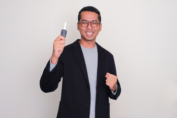 Asian casual businessman clenced fist showing excited while holding a car key - obrazy, fototapety, plakaty