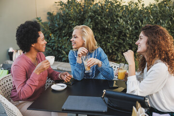 A Captivating Conversation Among Three Women at a Table In A Cozy Cafe