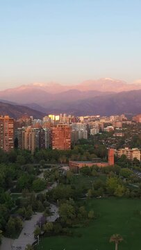 Las Condes Commune in Santiago and Andes Mountains at Sunset. Residential Buildings. Aerial View. Chile. Drone Flies Upwards. Vertical Video