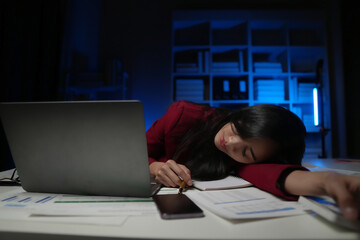 Exhausted Asian businessman working at his desk late at night