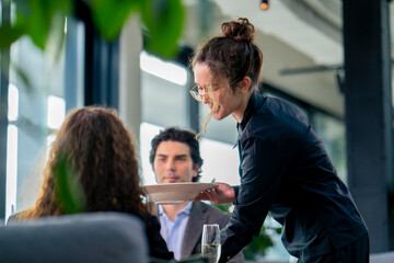 a girl waiter serves orders to guests the concept of hospitality and service in a high-class...