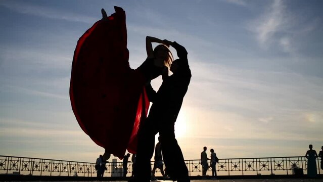 Silhouette of beautiful couple dancing on street against sky