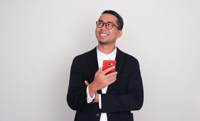Asian businessman holding mobile phone and looking to upper right corner with happy face
