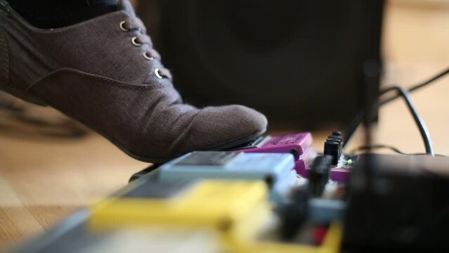 Close up of leg of guitarist pressing pedal in recording studio