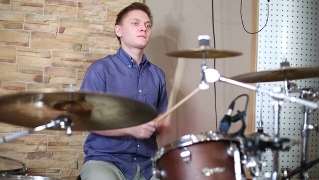 Happy young drummer plays in modern recording studio 