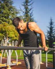 One man muscular male athlete training dips outdoor in sunny day