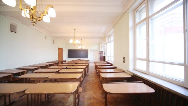 Empty small classroom with wooden desks and chandeliers 