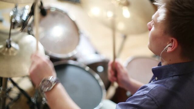 Back of young male drummer playing in modern recording studio 