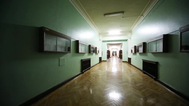 Long hallway with parquet flooring, green walls in university