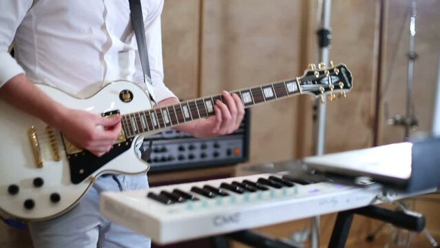 Hands of guy in white shirt playing guitar in recording studio