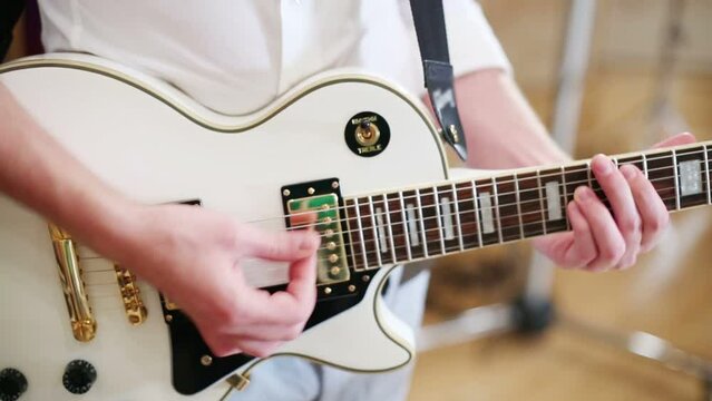 Hands of man playing guitar with mediator in recording studio