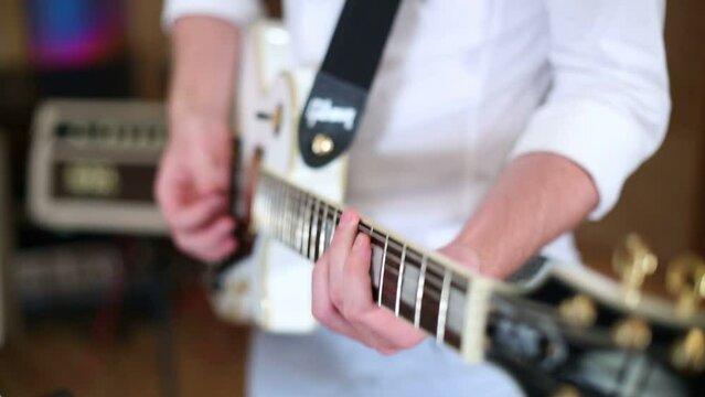 Hands of man playing guitar with mediator in recording studio