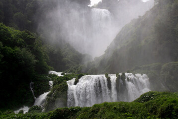 Landscape view of Cascata delle Marmore cascading waterfall and mist from water splashes around it...