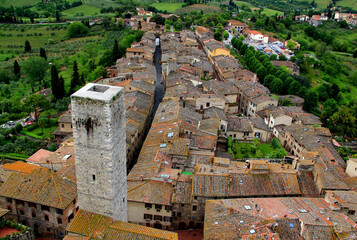 Aerial view of the historic part of the city with the medieval towers and green valley in the background in San Gimignano, near Siena, in Tuscany region of Italy - obrazy, fototapety, plakaty