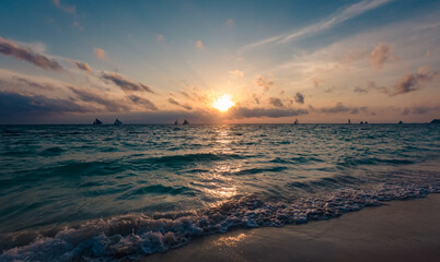 Amazing colors of tropical sunset. Sail boats silhouettes floating on ocean horizon. Ocean waves...