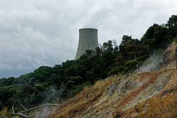 Cooling tower in a geothermal park with steam and smoke clouds billowing from the ground. Clean...