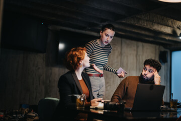 Executives working late in a corporate office, collaborating to plan and develop a successful project. They focus on data analysis, market research, and sales statistics for business growth.