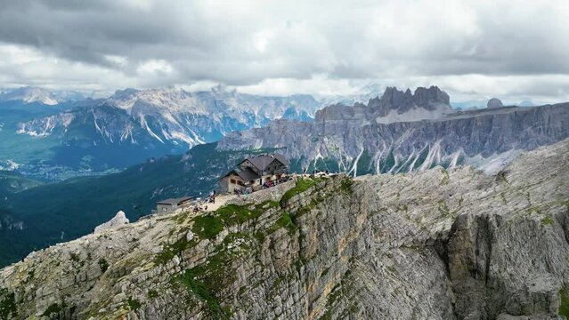 Aerial view of Rifugio Nuvolau, the oldest mountain hut refuge in the Dolomites, Italy. Clouds covering the mountains in the background. Beautiful destinations for hikers and alpinists. Cinematic shot