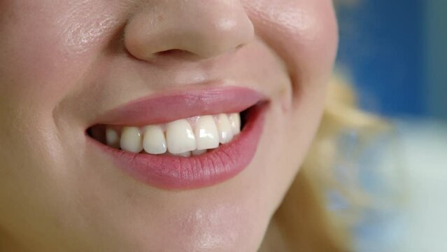 Close up of beautiful white straight teeth of young woman, lady biting lower lip, glowing bright face skin with light blush, healthy teeth, dental checkup. High quality 4k footage