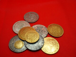 Spanish gold and silver coins, Shields and Reales, on a red background