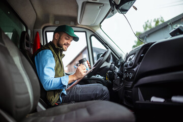 Young handsome man working in towing service and drinking coffee so he could get some energy