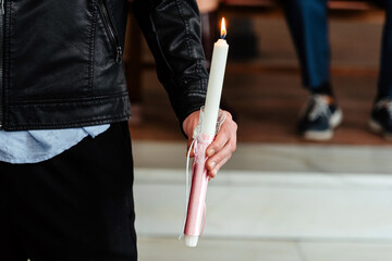 Detalle de la mano de un hombre sosteniendo una vela encendida en la iglesia. Concepto del...