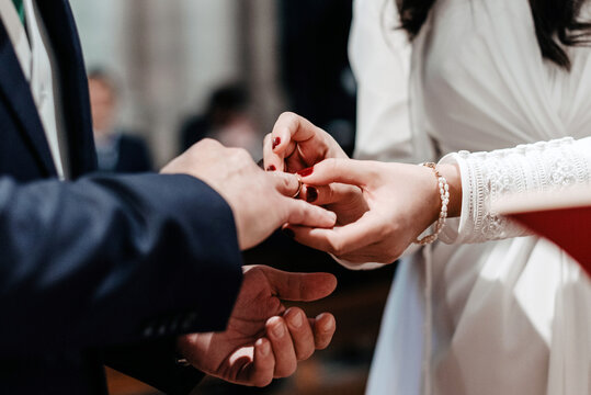 Una novia le coloca un anillo en el dedo a su futuro marido en el altar de una iglesia. Ceremonia de matrimonio seg&uacute;n la tradici&oacute;n cat&oacute;lica.