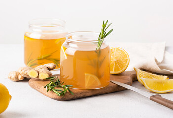 The process of preparing homemade kombucha with lemon, ginger, rosemary, light background