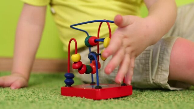 Hands of boy playing with wooden toy on floor in kindergarten