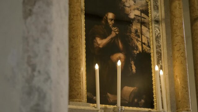 Reveal Shot of Picture, Painting of God, Creator, Jesus Praying, Surrounded With Candle Holders, Lit Candles, Painted Walls in Golden Colours, Inside Catholic, Christian Church.