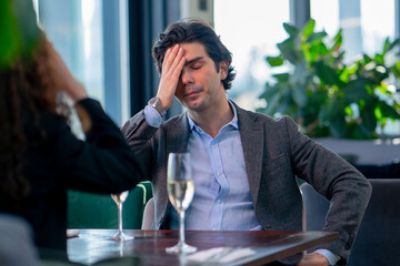 portrait of an upset nervous man sitting in a restaurant with a girl who is quarreling on a date conflict - obrazy, fototapety, plakaty