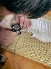violinmaker performing purfling to new raw violin top plate using loupe to check inlaid channel