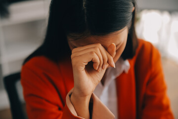 Asian women sitting in a home office With stress and eye strain.Tired businesswoman holding...