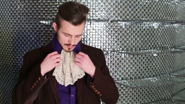 Man with a mustache in dress and lace tie against mirrored wall 
