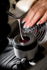 Female hands of a manicurist put pink gel on a brush