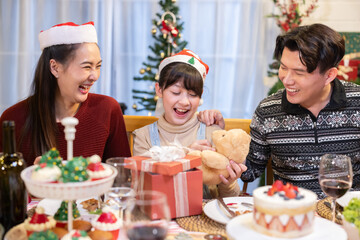 Asian daughter open her Christmas gift box with her parent