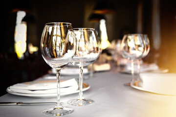 Served dinner table set in a luxury restaurant. Restaurant interior with window lighting. - obrazy, fototapety, plakaty