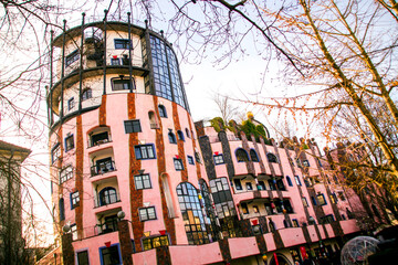 December 16, 2023: Gruene Zitadelle green citadel Magdeburg, Germany famous Arthouse of the Architect Friedensreich Hundertwasser, pink walls of the zitadelle,, tower and trees, zoom out, askance line - obrazy, fototapety, plakaty