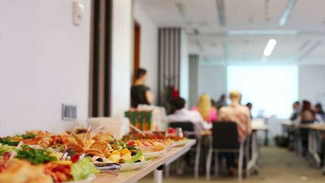 Many plates with cold appetizers on table and business meeting