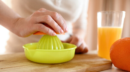 Obraz na płótnie Canvas Girl making orange juice at kitchen