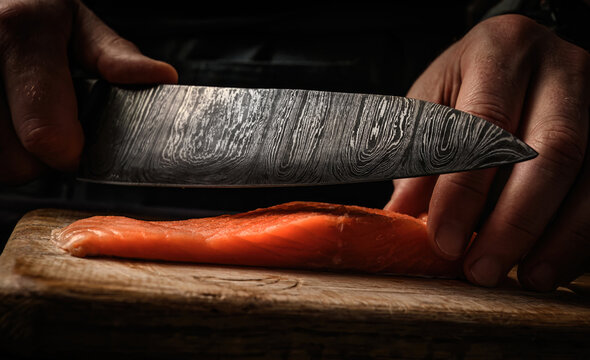 Sushi chef cuts raw salmon with knife