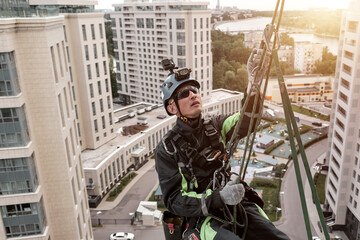Industrial mountaineering worker hangs over residential building