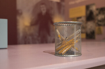 close-up of short yellow colored pencils in a mesh container with a blurred background