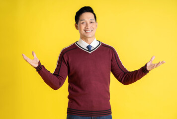 Portrait of an Asian man wearing a Christmas sweater and posing on a yellow background