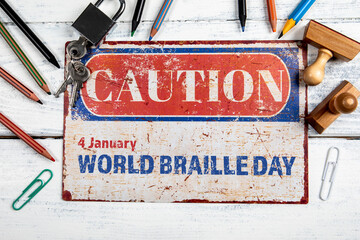 World Braille Day. 4 January. Metal CAOTION plate with text on a white wooden background