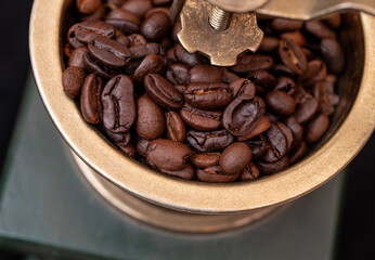 Closeup view of golden coffee grinder with roasted beans