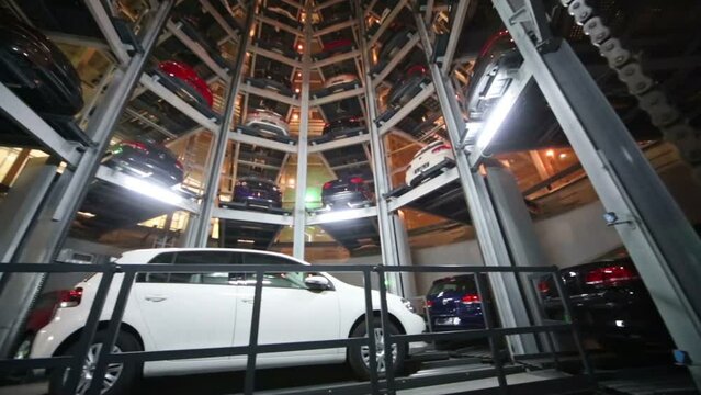 White car on lift and many other cars in tower to store