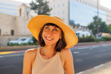 Young beautiful woman walks through the streets on a sunny summer day. Portrait of a girl in a hat.