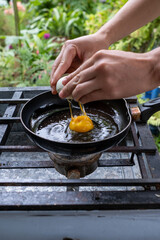 An egg dropping into a frying pan to be fried