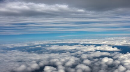 Naklejka premium Aerial view of the sky through an airplane window, showcasing fluffy white clouds and a vast blue expanse. Aerial view of white fluffy clouds in the blue sky.